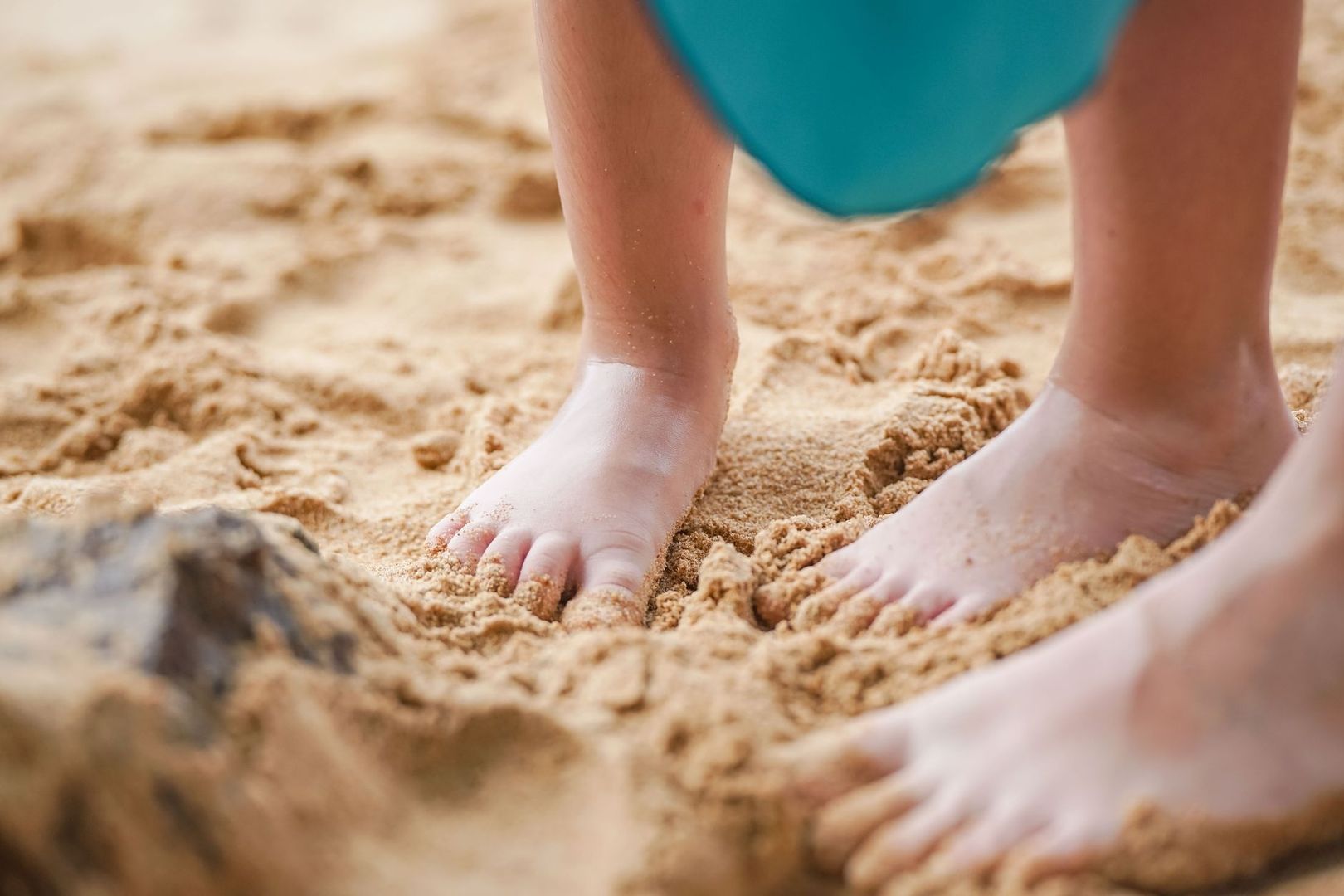 Närbild av ett barns bara fötter i mjuk sand under sensorisk lek