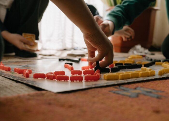 Flera personer placerar färgade spelpjäser på ett brädspel